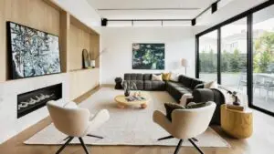 Modern living room interior with stylish sectional sofa, natural wood accents, large windows, and minimalist décor.