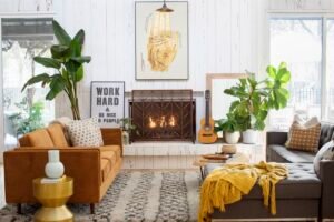 Cozy living room with a mustard sofa, gray chaise lounge, fireplace, indoor plants, and warm decor