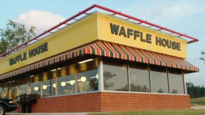 Front view of a Waffle House restaurant building with yellow signage and striped awning