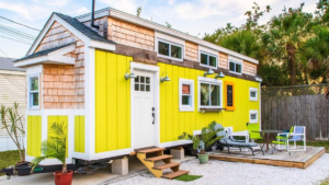 Bright yellow tiny house with outdoor seating area showcasing tiny house living